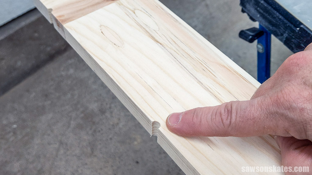 Finger pointing to a weep hole in the bottom of a DIY storm window