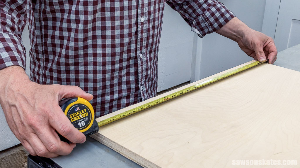 Using a tape measure to measure a piece of plywood