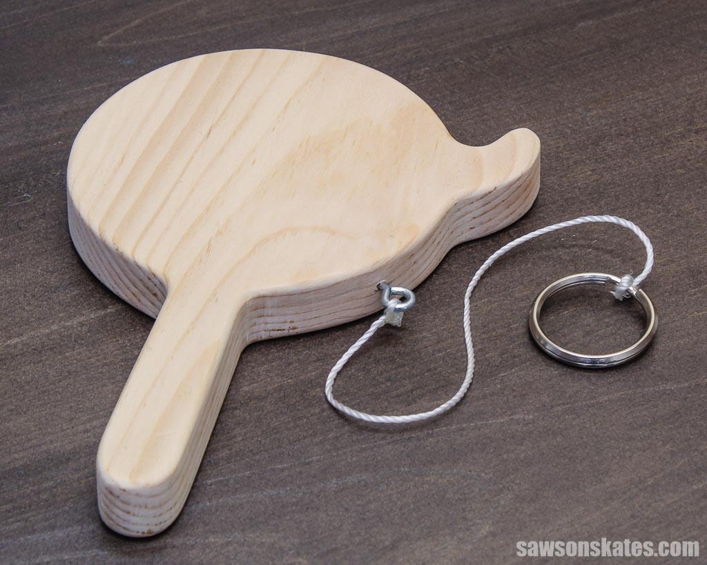 DIY handheld hook-and-ring game on a dark brown table