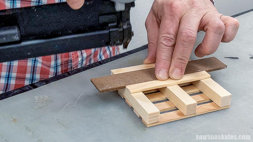 Using a pin nailer to attach the middle deck board to the underside of a DIY mini pallet coaster