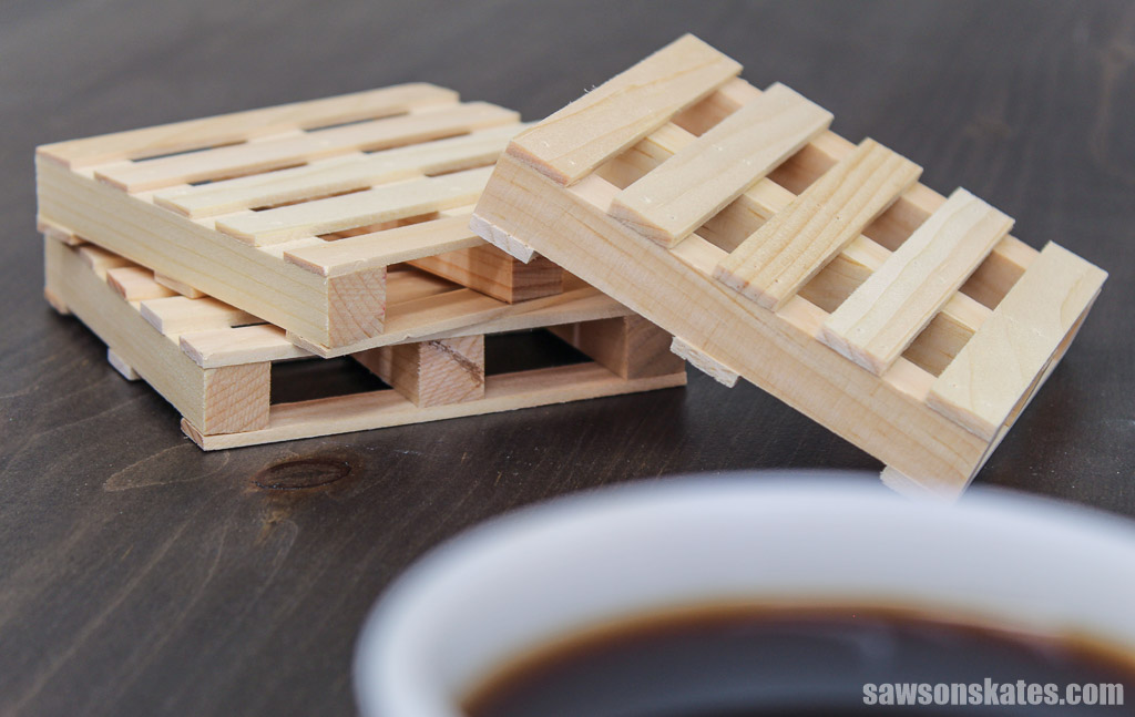 Three DIY mini pallet coasters in the background and the rim of a coffee cup in the foreground
