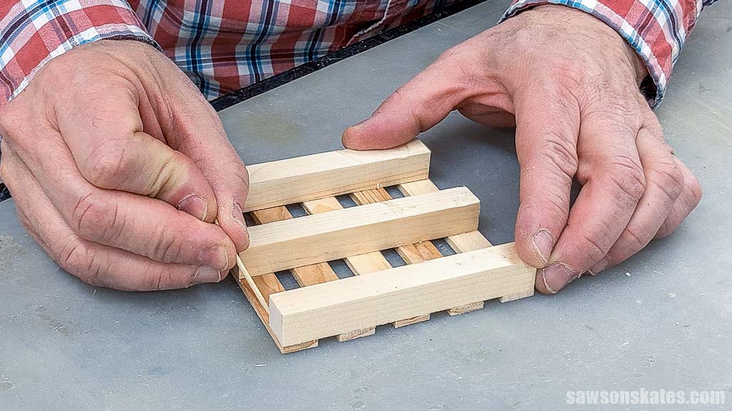 Using a toothpick to remove excess glue from a mini DIY pallet coaster