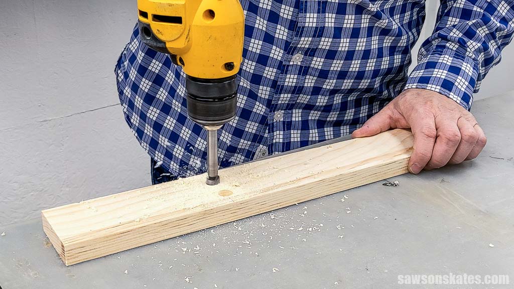 Using a drill to make holes in a wood board for a DIY bow maker