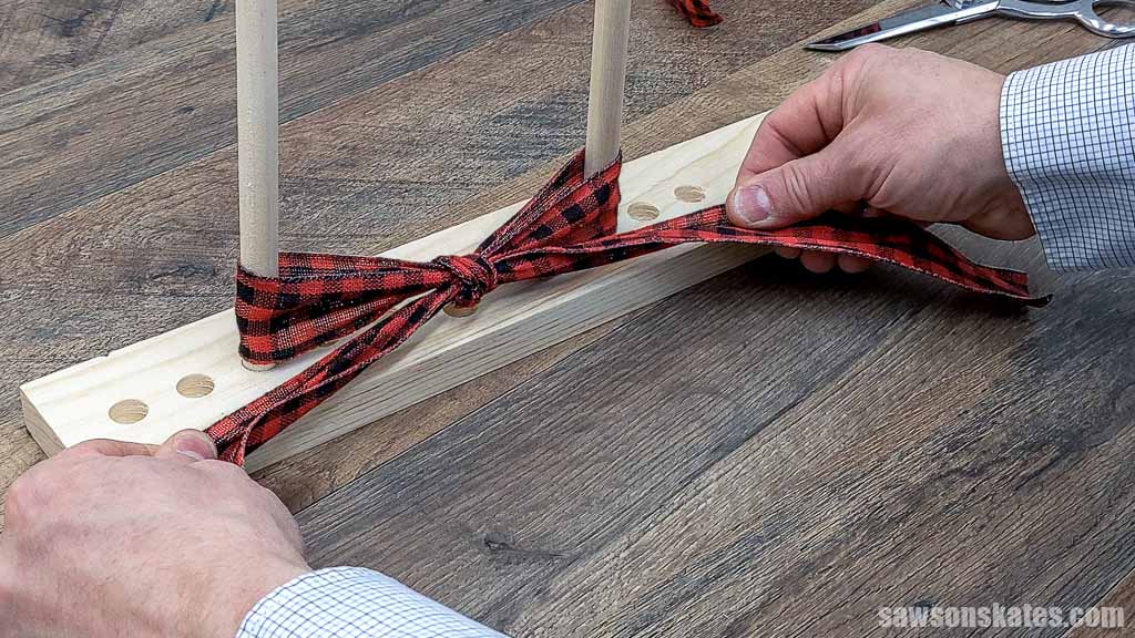 Hands pulling the tails snug on a DIY wooden dowel bow maker