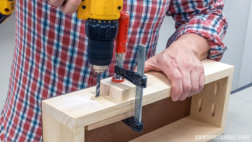 Drilling holes for screws that will attach knobs to a DIY toolbox's drawer