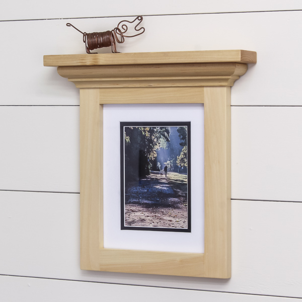 Wall-mounted picture frame with shelf attached at the top