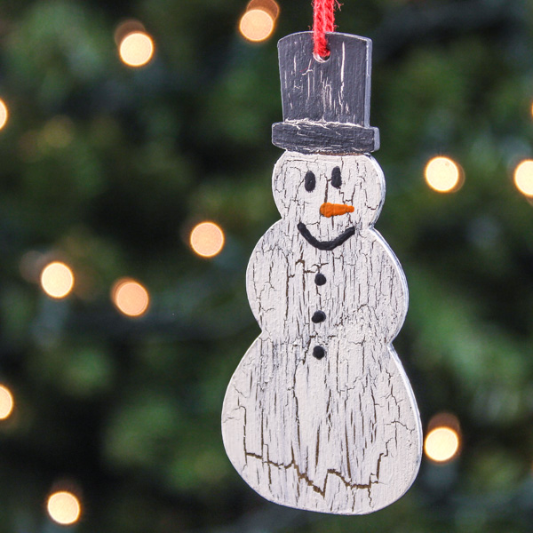 Wooden crackle painted DIY snowman ornament hanging on a Christmas tree