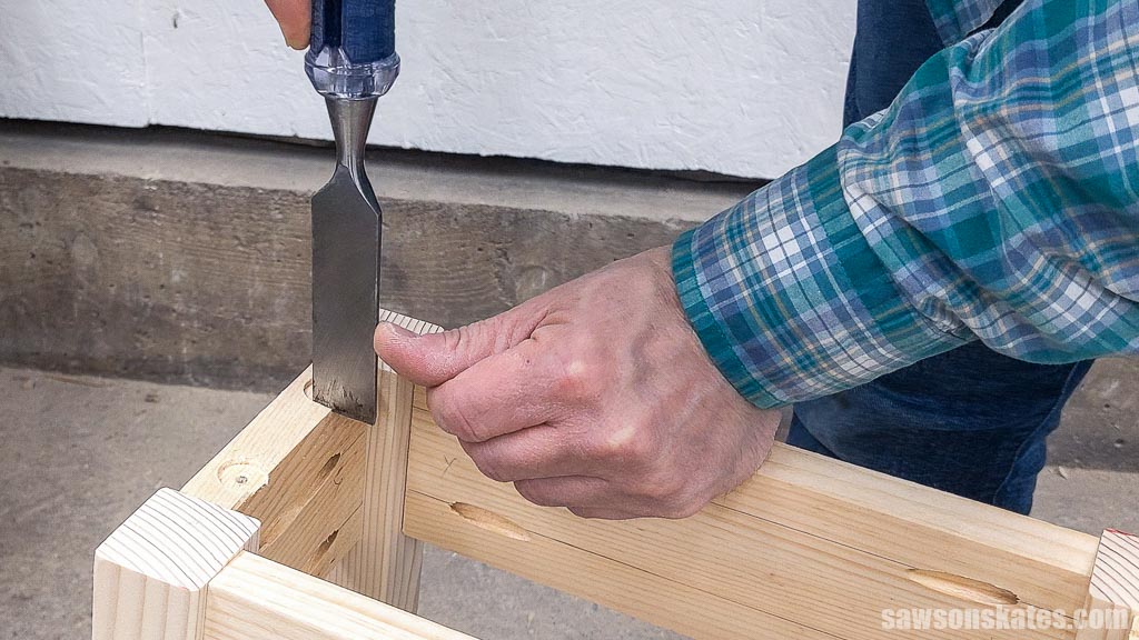 Hands using a chisel to square a hole for a table top fastener