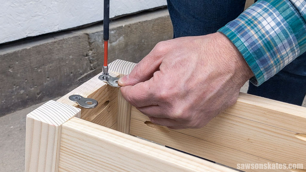 Attaching a table top fastener to a DIY bedside table's apron with a screw