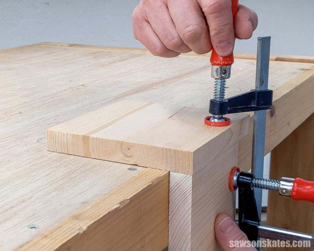 Using a clamp to hold a piece of wood on a workbench