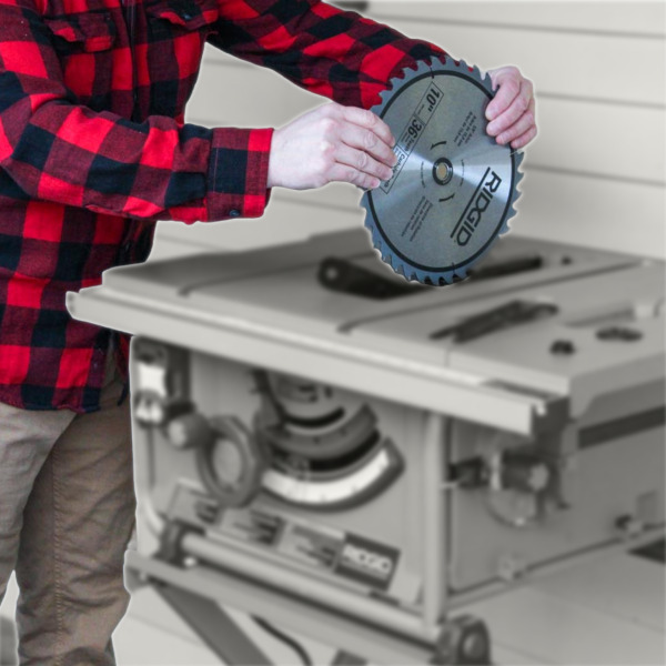 Hands putting a blade into a blurry, grayscale table saw
