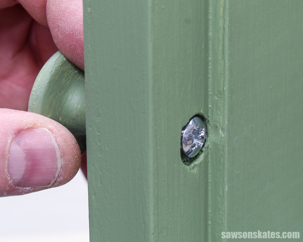 Close up of a knob's screw in a counterbore hole on the back of a cabinet door