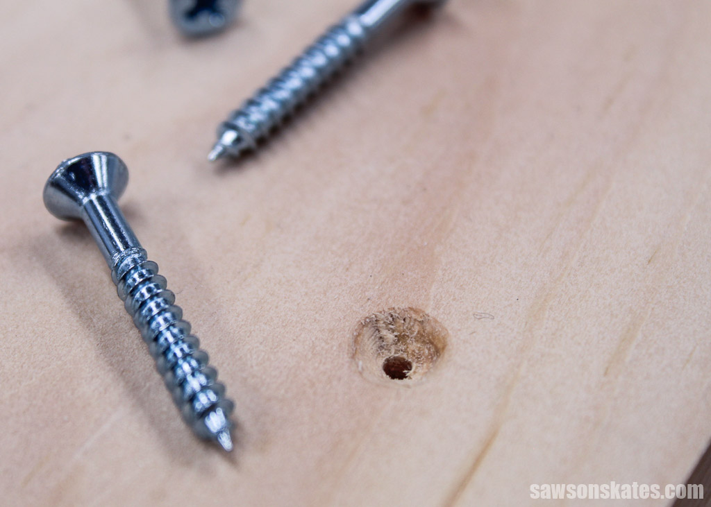 Several wood screws laying next to a countersink hole
