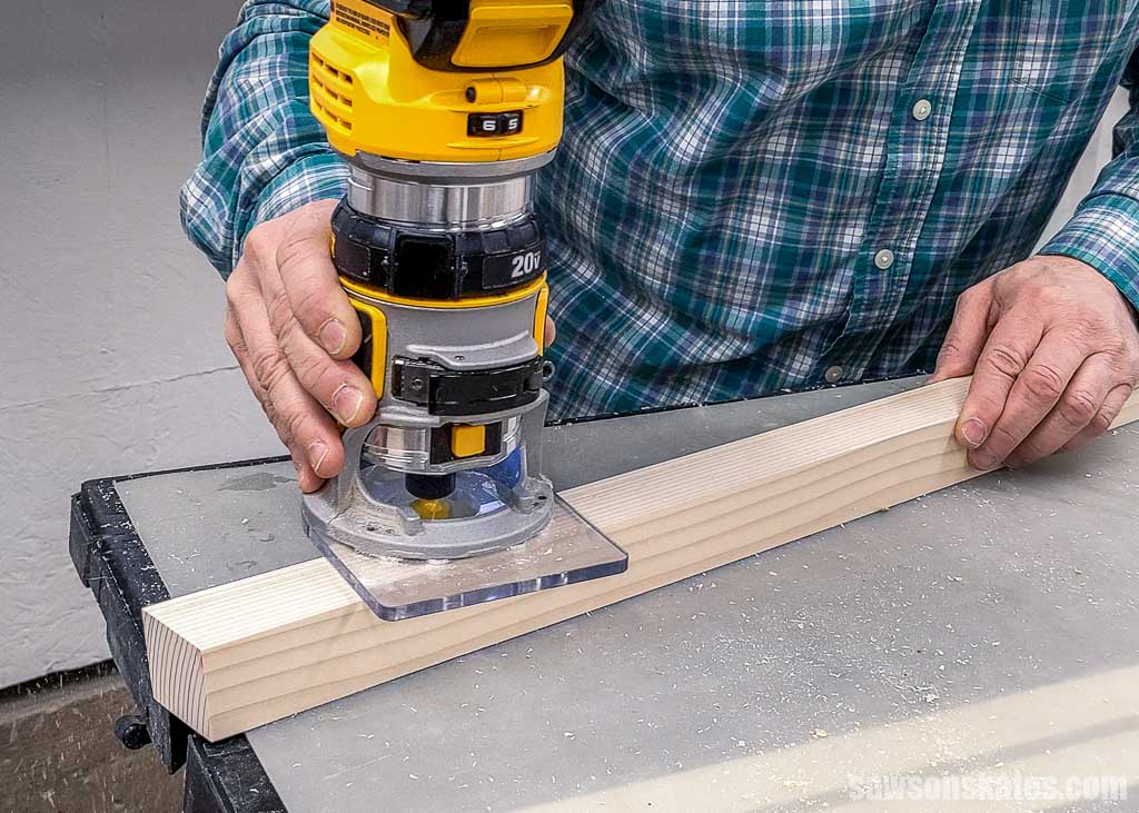 Using a handheld router to round over the cut edges of a 2x4 that was cut in half with a table saw