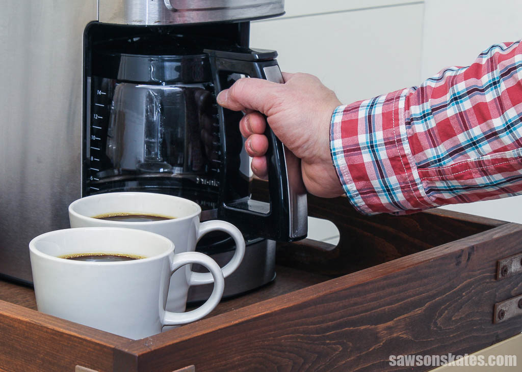 Hand removing a coffee pot from DIY coffee cart