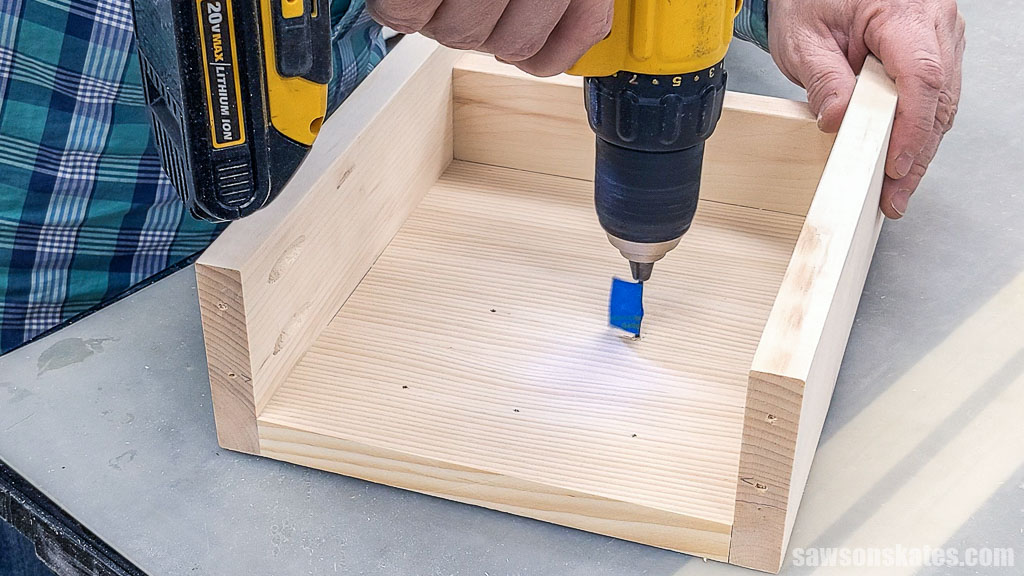 Using a drill to make a pilot hole in board