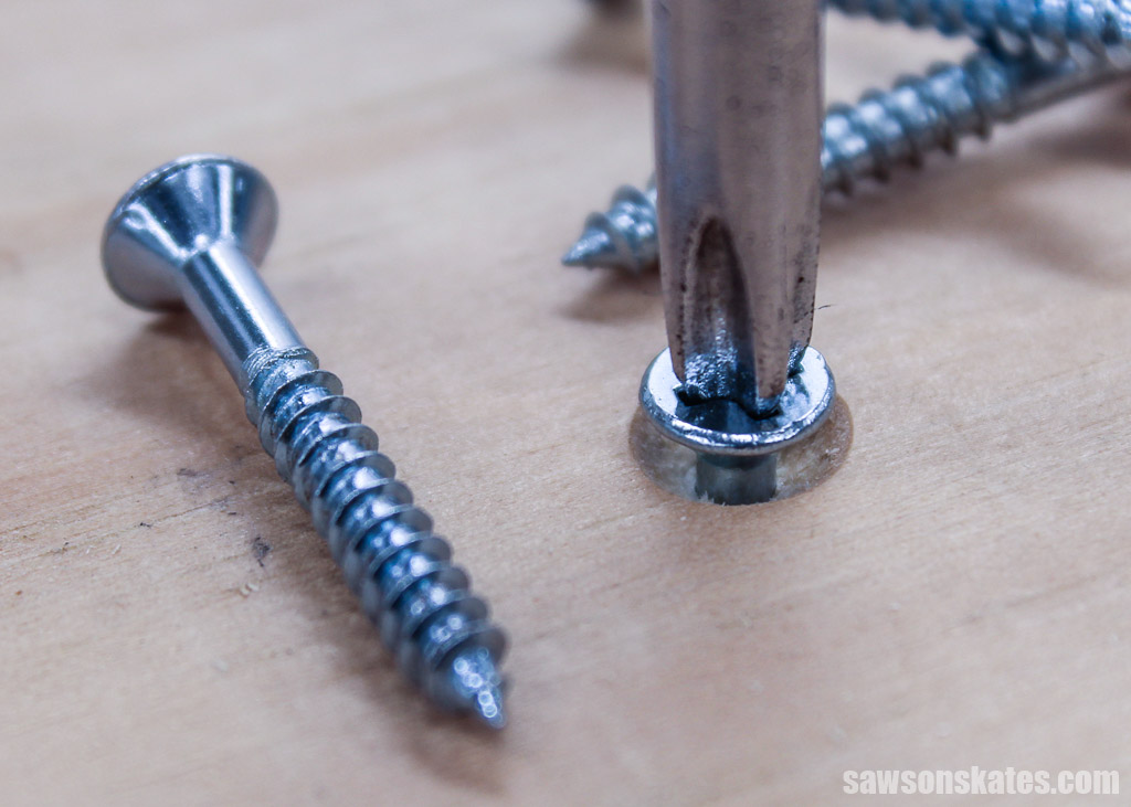 Screwdriver driving a screw into a countersink hole surrounded by several screws