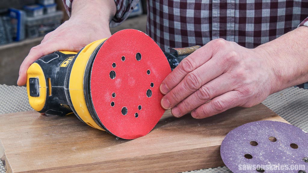 Hand removing a sanding disc from a power sander