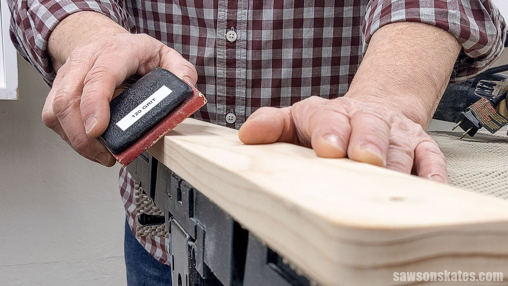 Using a sanding block to knock off a board's sharp edges.