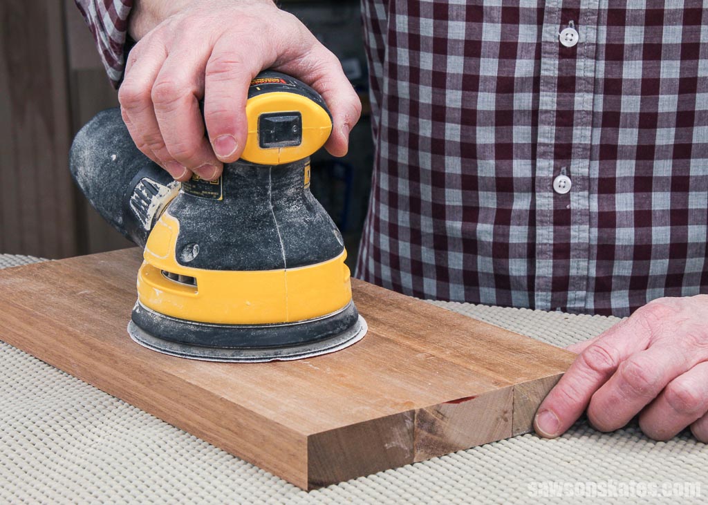 Using a power sander to smooth a piece of wood