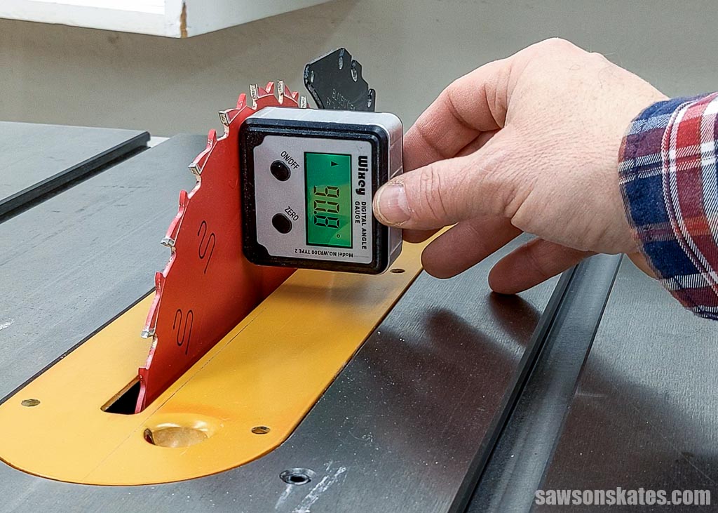 Hand placing digital angle gauge on a table saw blade