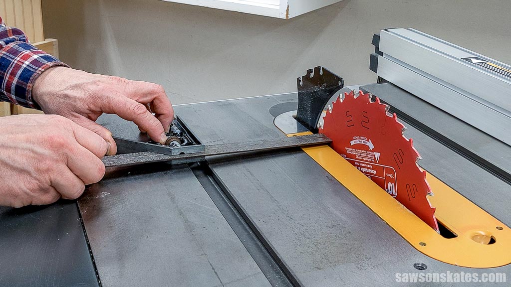 Checking the back of a table saw's blade for parallel with a combination square during a table saw tune up