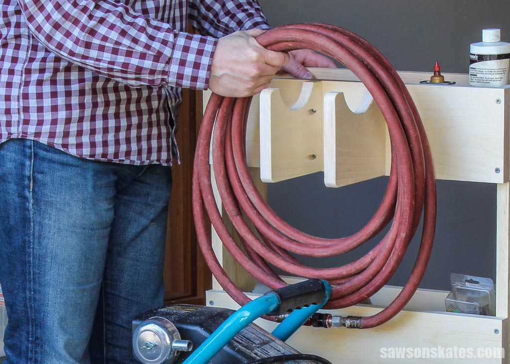 Hand removing an air hose from a DIY compressor cart's hose holder