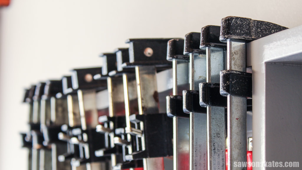 Closeup of bar clamps organized on a DIY clamp rack