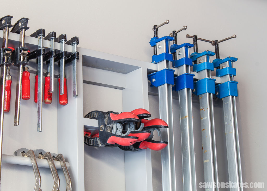 Looking up at an assortment of woodworking clamps on a DIY wall-mounted rack