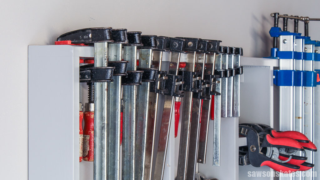 Assortment of bar clamps stored on a DIY wall-mounted organizer