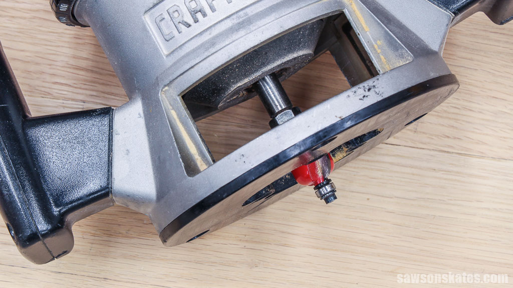 A red router bit protruding from a fixed-base router