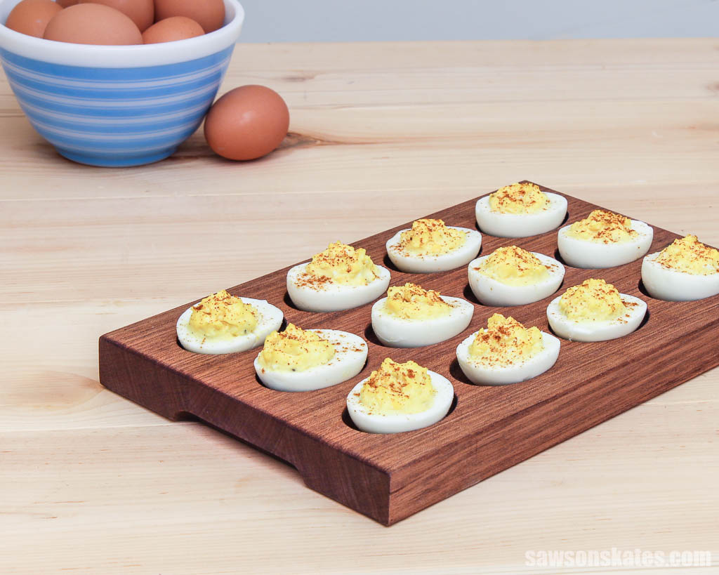Wooden DIY deviled egg tray on a table with a bowl of eggs in the background