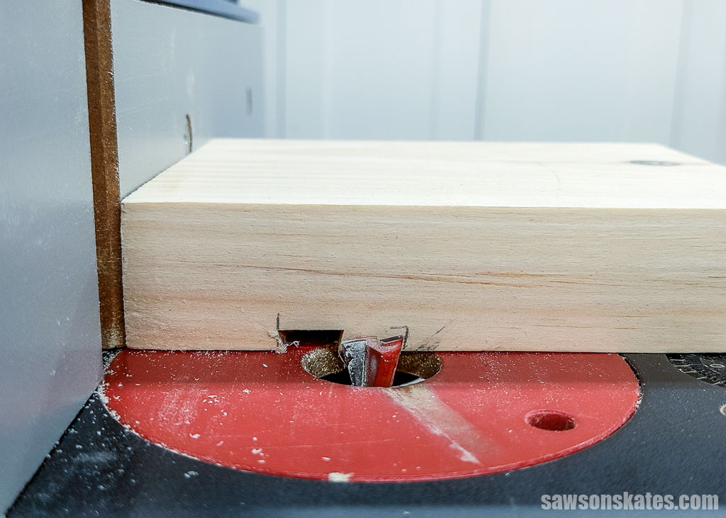 Positioning a raised trivet's top against a dovetail bit in a router table for a second cut