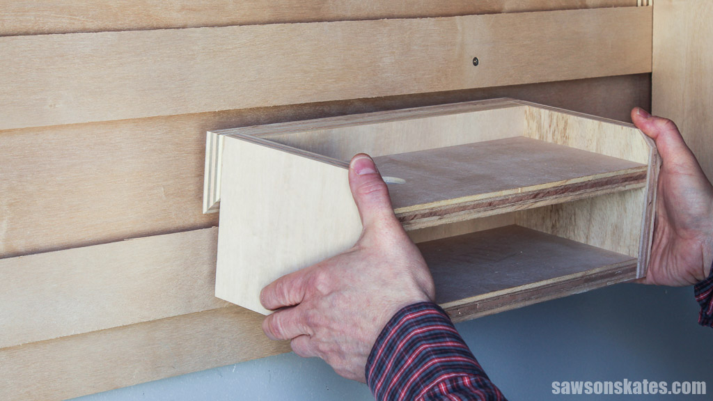 Hands mounting a DIY jigsaw rack on a French cleat wall