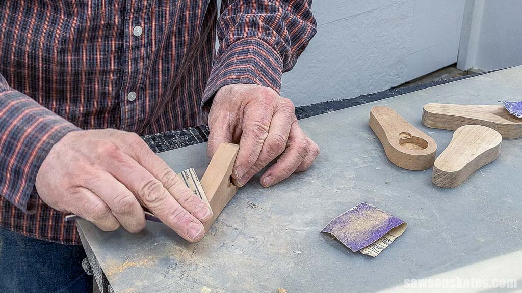 Using sandpaper to smooth the sides of a wooden DIY bottle opener