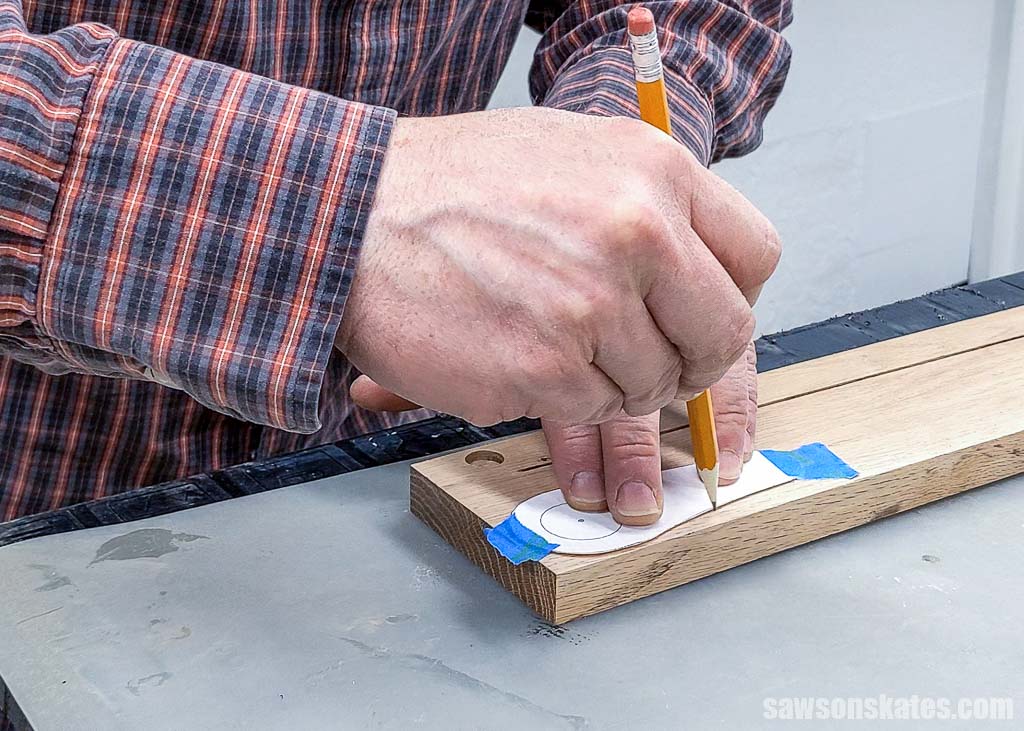 Tracing a bottle opener template onto a a piece of wood with a pencil