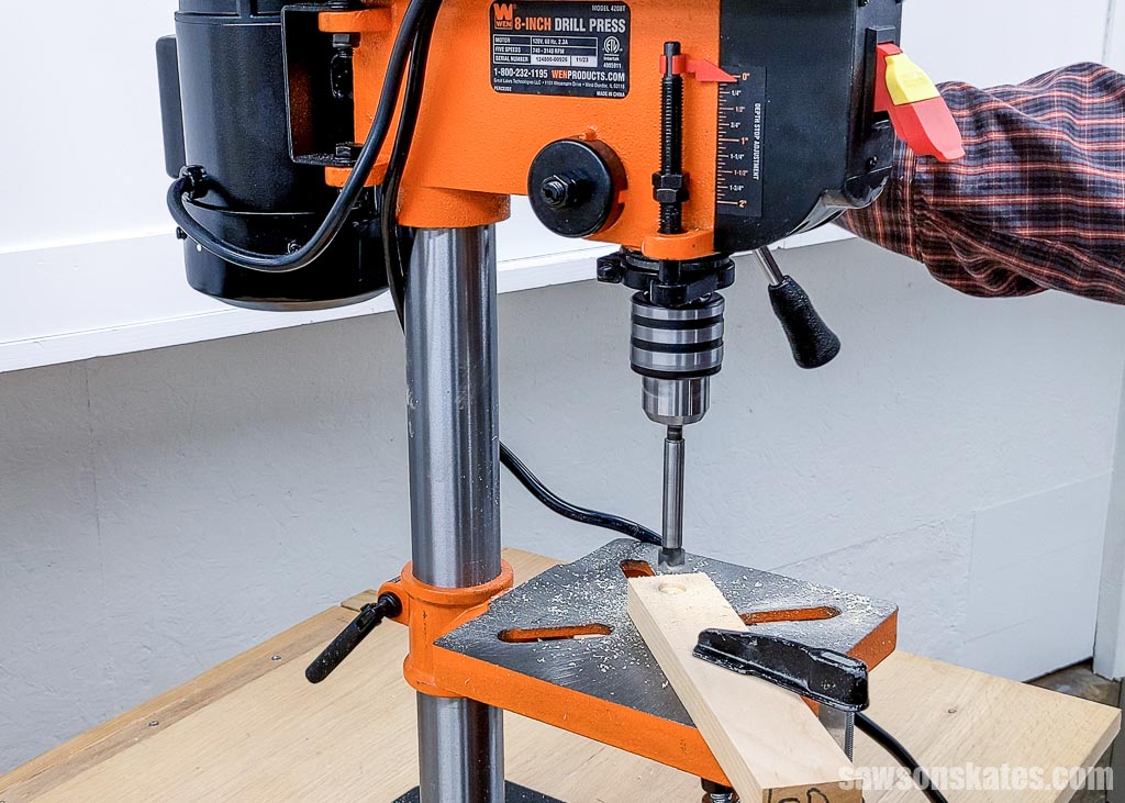 Drilling a test hole into a piece of wood with a drill press
