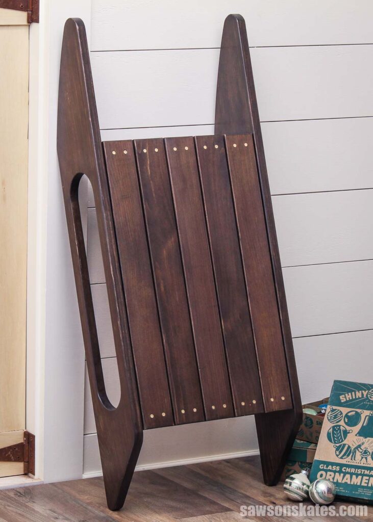 Old-time-style sled leaning against a wall with vintage ornaments next to it.