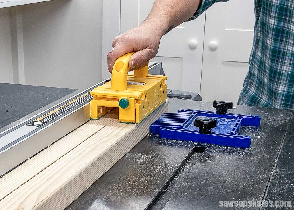 Using a push block and featherboard to cut a 2x4 lengthwise on a table saw