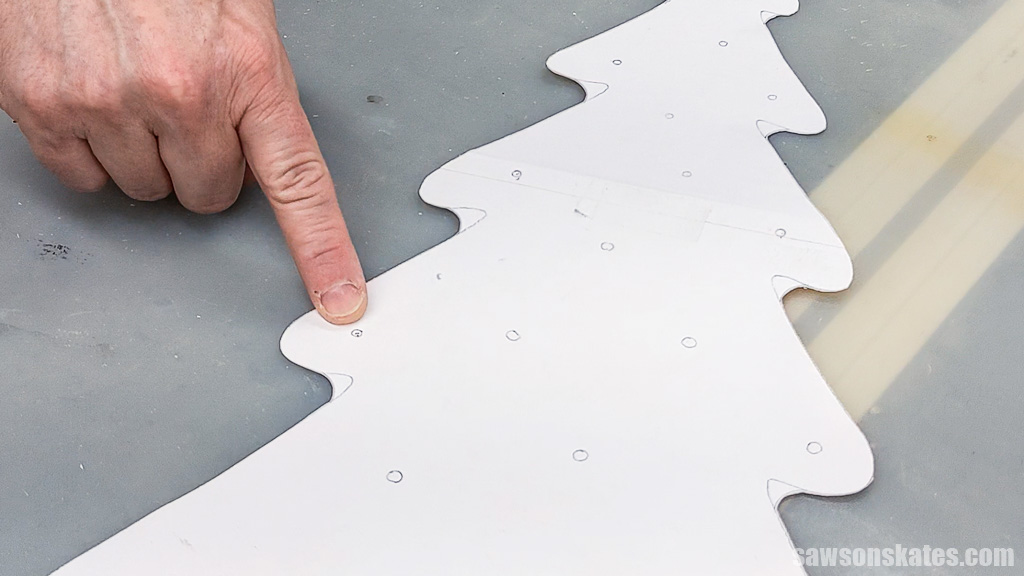 Finger pointing to a missing light location on a Christmas tree pattern