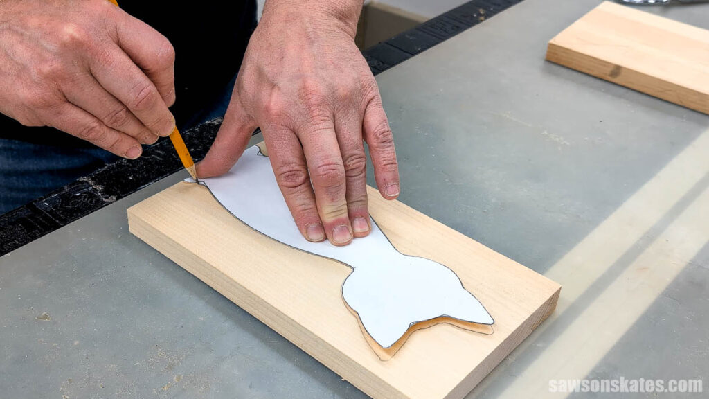 Tracing a cat template onto a board with a pencil