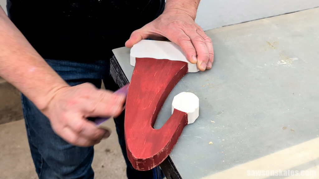 Using sandpaper to distress the edges of a wooden Santa hat
