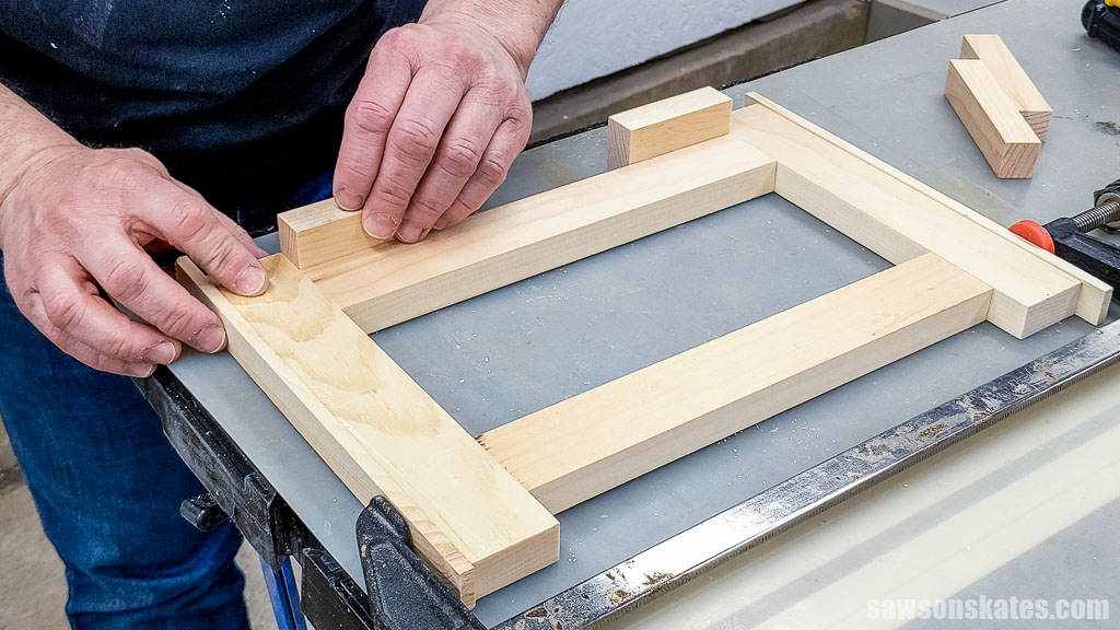 Placing a piece of scrap wood at the base of each leg to ensure proper spacing