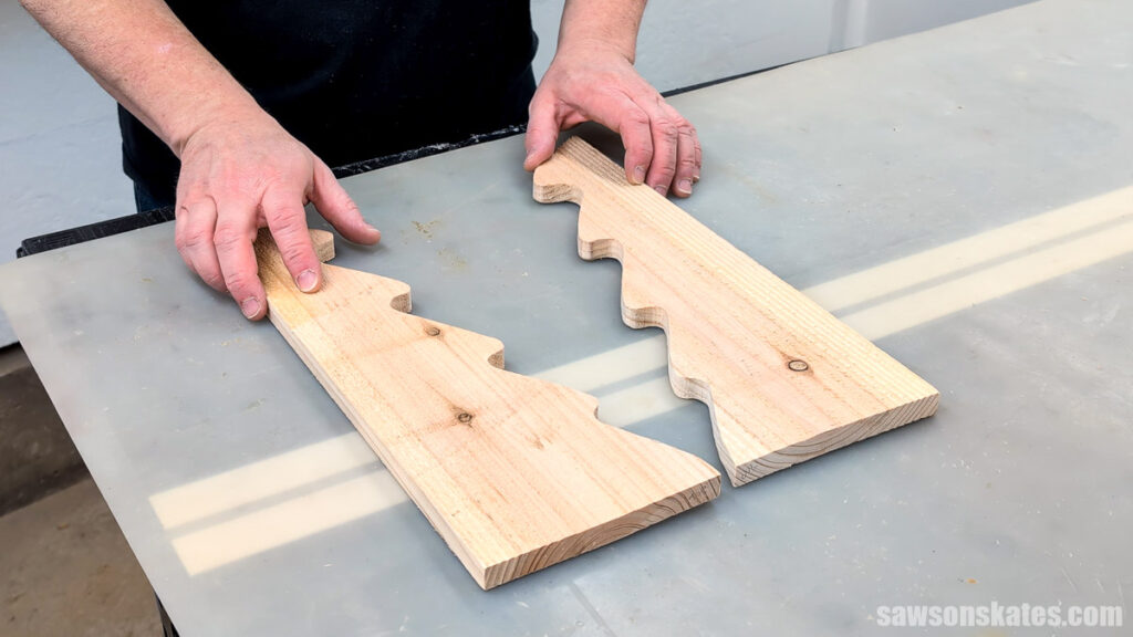 Hands holding scrap boards after a Christmas tree was cut out