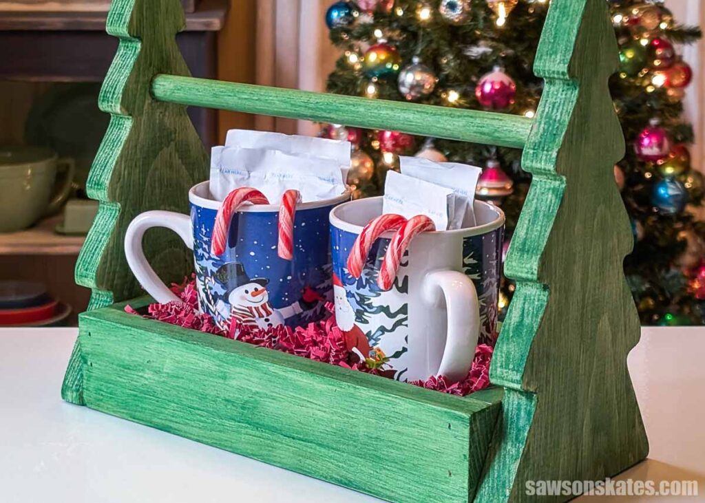 Handmade wooden tree-shaped hot cocoa caddy with mugs, cocoa packets and candy canes
