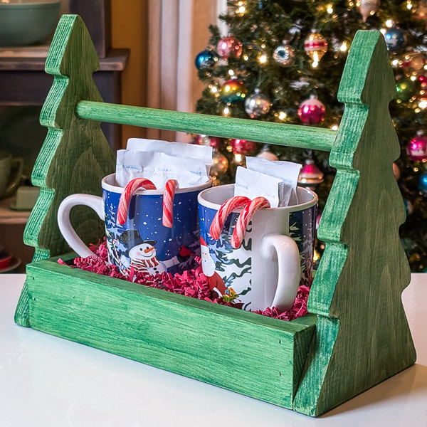 Handmade wooden tree-shaped hot cocoa caddy with mugs, cocoa packets and candy canes