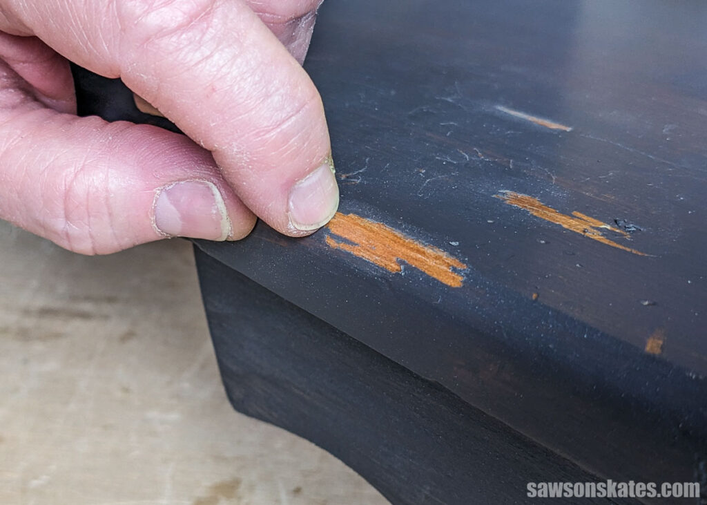 Finger nails scratching paint off of a wooden project