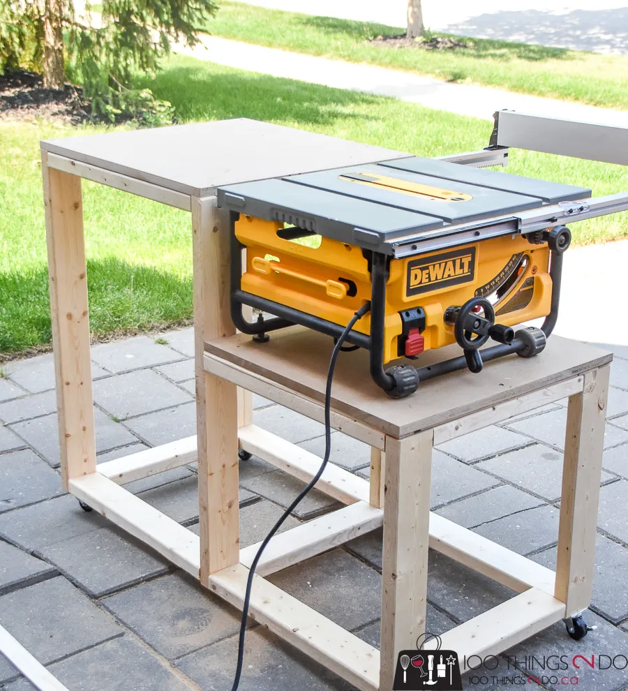 Portable DeWalt table saw mounted on a DIY wooden workbench with an outfeed table and caster wheels.