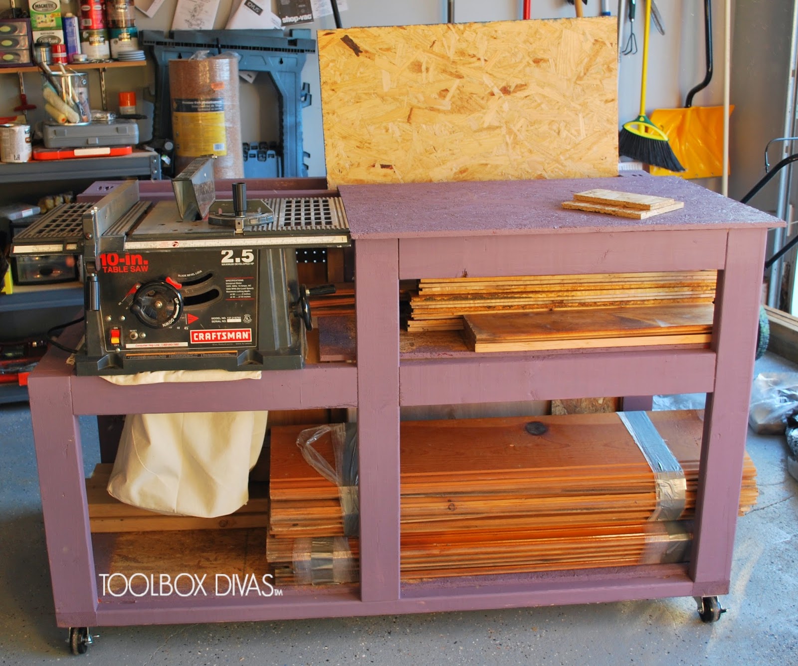 Table saw built into a painted DIY workbench with an extended top, lower shelves for lumber storage, and casters in a garage workshop.