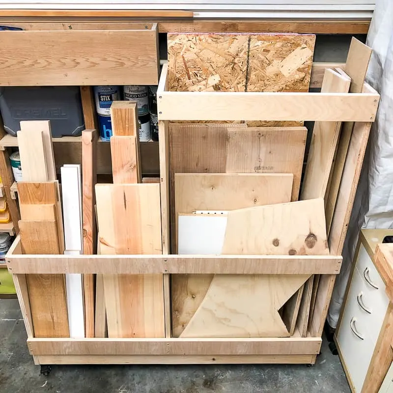 Rolling DIY scrap wood cart with divided storage sections holding plywood offcuts, hardwood boards, OSB scraps, and sheet goods.
